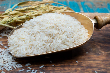 Organic white uncooked rice and dried basmati rice plant onwooden table