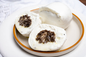 White balls of Italian soft cheese Mozzarella di Bufala Campana stuffed with black truffles mushrooms