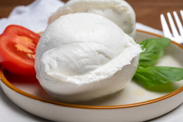 White balls of Italian soft cheese Mozzarella di Bufala Campana served with fresh green basil and red tomato