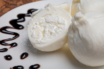 Eating of fresh handmade soft Italian cheese from Puglia, white balls of burrata or burratina cheese made from mozzarella and cream filling served with balsamico cream