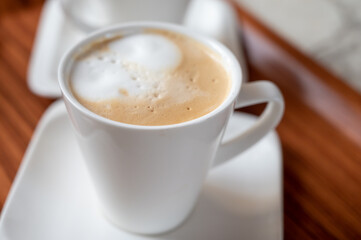 White cup of coffee latte served in outdoor cafe in France