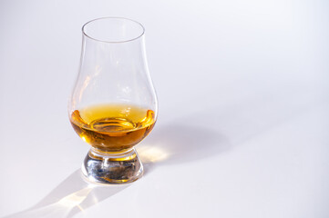 Tulip-shaped tasting glass with dram of Scotch single malt or blended whisky on white background - obrazy, fototapety, plakaty