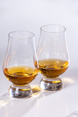 Tulip-shaped tasting glasses with dram of Scotch single malt or blended whisky on white background