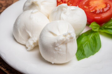 Eating of fresh handmade soft Italian cheese from Puglia, white balls of burrata or burratina cheese made from mozzarella and cream filling