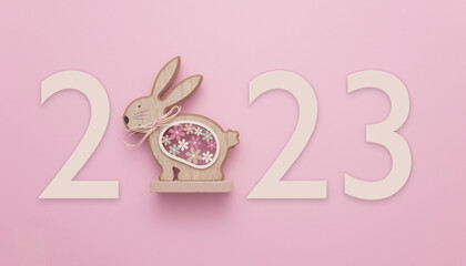 In celebration of Easter or the Chinese New Year 2023, the year of the Rabbit. A wooden rabbit on a pink background displaying the number 2023.