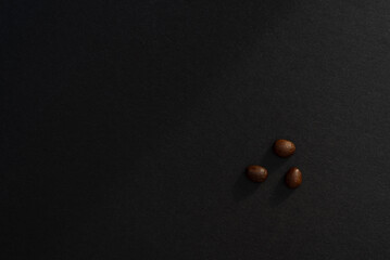 Three coffee beans on a black background, minimalistic design. Beauty is in simplicity