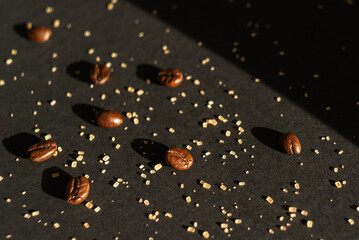 Coffee beans and cane sugar in a beam of light on a black paper background