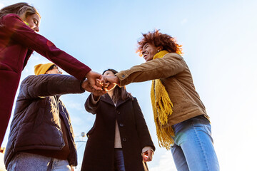 Multiracial group of friends giving fist bump together showing unity outdoors