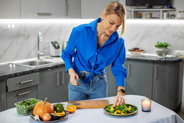 Young adult woman preparing vegetable salad in kitchen. Concept of healthy food, diet and eco food.