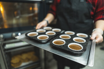 Unrecognizable pastry chef showing ready to bake chocolate muffins. Home made cupcakes baked in kitchen oven. High quality photo