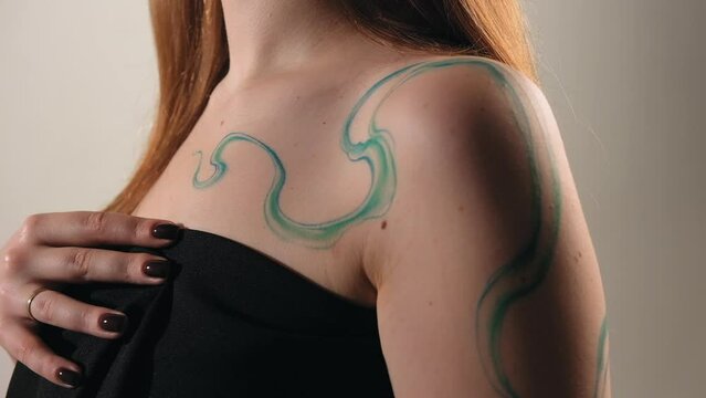 abstract tattoo on a girl's body. ready-made tattoo in the form of a wave. the model stands in the studio and shows a tattoo