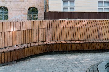 A long wooden bench in the city square. Decoration. Park Bench. Scenery. Elegant. Contemporary....