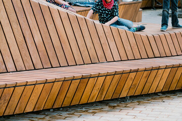 A long wooden bench in the city square. Recreation. Fun. Space. Plank. Object. Road. Street....