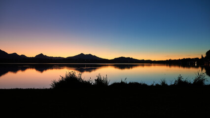Hopfensee im traumhaften Abendlicht mit Bergsilhouette, Bayern, Deutschland