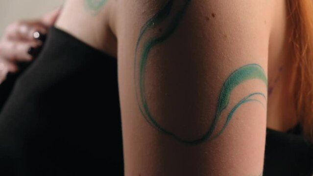 abstract tattoo on a girl's body. ready-made tattoo in the form of a wave. the model stands in the studio and shows a tattoo