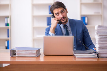 Fototapeta premium Young businessman employee and too much work in the office
