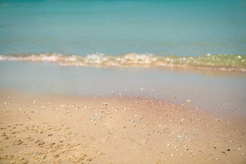 Sand with blurred waves at the background. Sandy beach, summer vacation. Copy space.