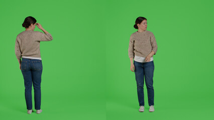 Displeased woman doing pushing action on camera, trying to push something outside standing over full body greenscreen backdrop. Discontent girl moving thing in studio, expressing rejection.