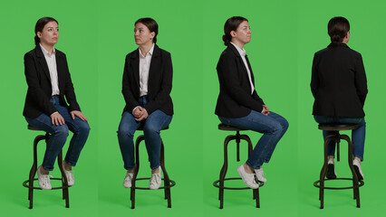 Company employee sitting on chair and waiting on camera, full body greenscreen backdrop. Young...