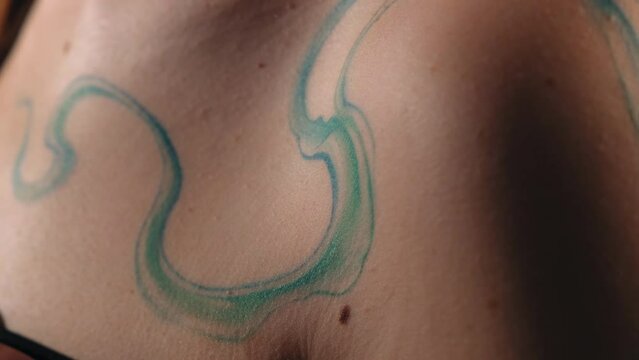 abstract tattoo on a girl's body. ready-made tattoo in the form of a wave. the model stands in the studio and shows a tattoo