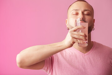 Colour obsession concept. Bearded hipster muscular guy drinking fruit juice over pink background....