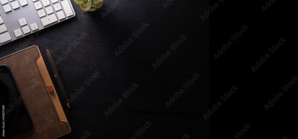 Poster stylish workspace with notebook, smart phone and wireless keyboard on black wooden table. top view w