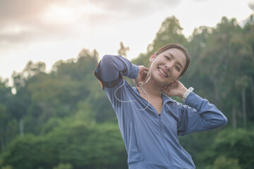 Beautiful sporty woman warming up before fitness training session at the park in sunrise light.