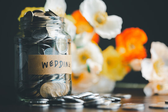 Save money for wedding and planning wedding concept. Sustainable financial goal for family life or married life. Miniature wedding on rows of rising coins, depicts savings or growth for new family.