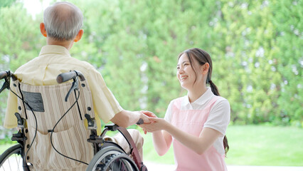 車椅子に乗った高齢者を介護する女性ヘルパー