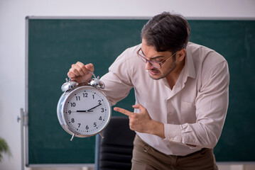 Young male teacher sitting in the classroom