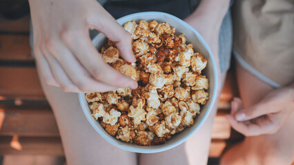 Friends eating popcorn on the street. Close-up of hands.