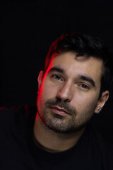 Cara de hombre guapo con luz roja a un costado y fondo negro