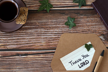 Thank You, LORD, handwriting on paper with envelope, pen, holy bible book, and cup of coffee on wooden background. Top view, copy space. Christian thanksgiving, gratitude, blessing, and praise to God