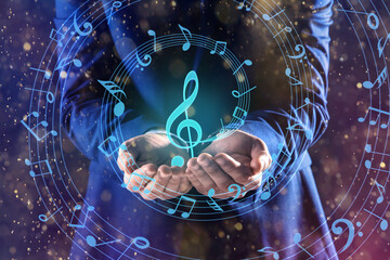 Musician holding staff with music notes and symbols on color background, closeup