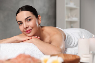 Beautiful happy woman relaxing on massage table in spa salon