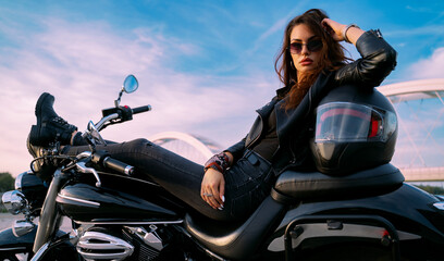 Amazing attractive confident woman laying on top of the motorcycle resting on the helmet 