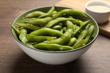 Bowl with green edamame beans in pods on wooden table