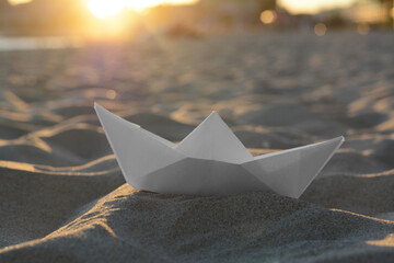 Obraz premium Beautiful white paper boat on sand outdoors, closeup