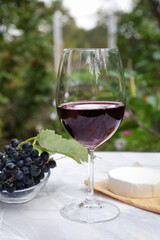 Glass of red wine and snacks served on white marble table outdoors