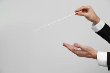 Professional conductor with baton on light grey background, closeup. Space for text