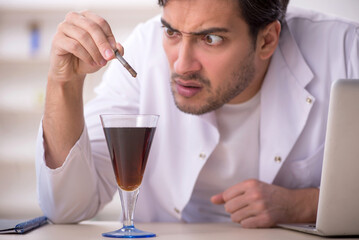 Young male chemist examining soft drink