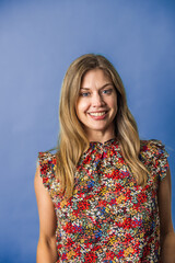 An attractice brunette woman in her forties wearing a floral top against a purple background