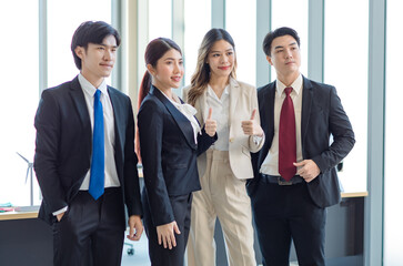 Millennial Asian young professional successful male female businessmen businesswomen in formal suit standing smiling side by side smiling showing thumbs up together in company office workstation