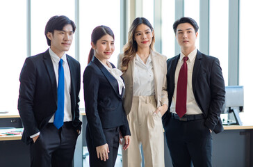 Millennial Asian young professional successful male female businessmen businesswomen in formal suit standing smiling side by side smiling in company office workstation.