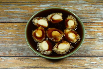 Traditional stew of fresh and organic abalone dressing with soy sauce serving on the plate. Famous luxury and oriental menu in Chinese restaurant. 