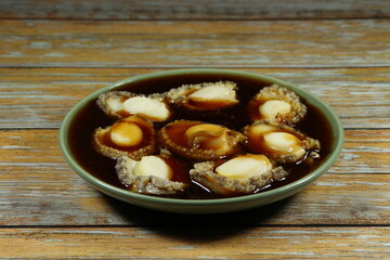 Traditional stew of fresh and organic abalone dressing with soy sauce serving on the plate. Famous luxury and oriental menu in Chinese restaurant. 