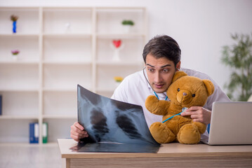 Young male doctor holding toy bear