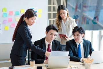 Millennial Asian young professional successful  businessman in formal suit with female and male businessman colleague in formal suit brainstorming  in company office room.
