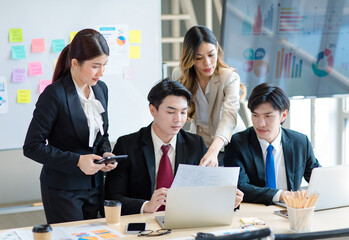 Millennial Asian young professional successful  businessman in formal suit with female and male businessman colleague in formal suit brainstorming  in company office room.