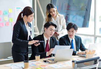 Millennial Asian young professional successful  businessman in formal suit with female and male businessman colleague in formal suit brainstorming  in company office room.